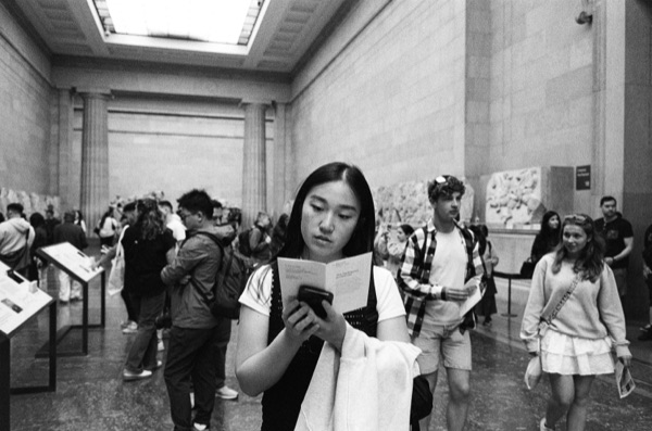 Lily reading a gallery guide in a museum, black and white